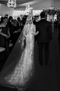 bride walking down aisle in long lace veil